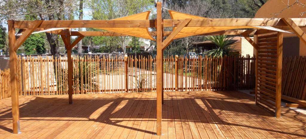 pergola en toile posé surt une terrasse en bois avec des barrières bois design dans un restaurant de plage a vias