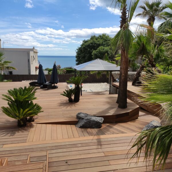 Grande terrasse en bois Itauba avec vue mer Méditerranée, palmiers et aménagement paysager tropical