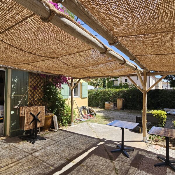 Pergola en eucalyptus avec toiture en toile coco quadrillée installée sur une terrasse professionnelle