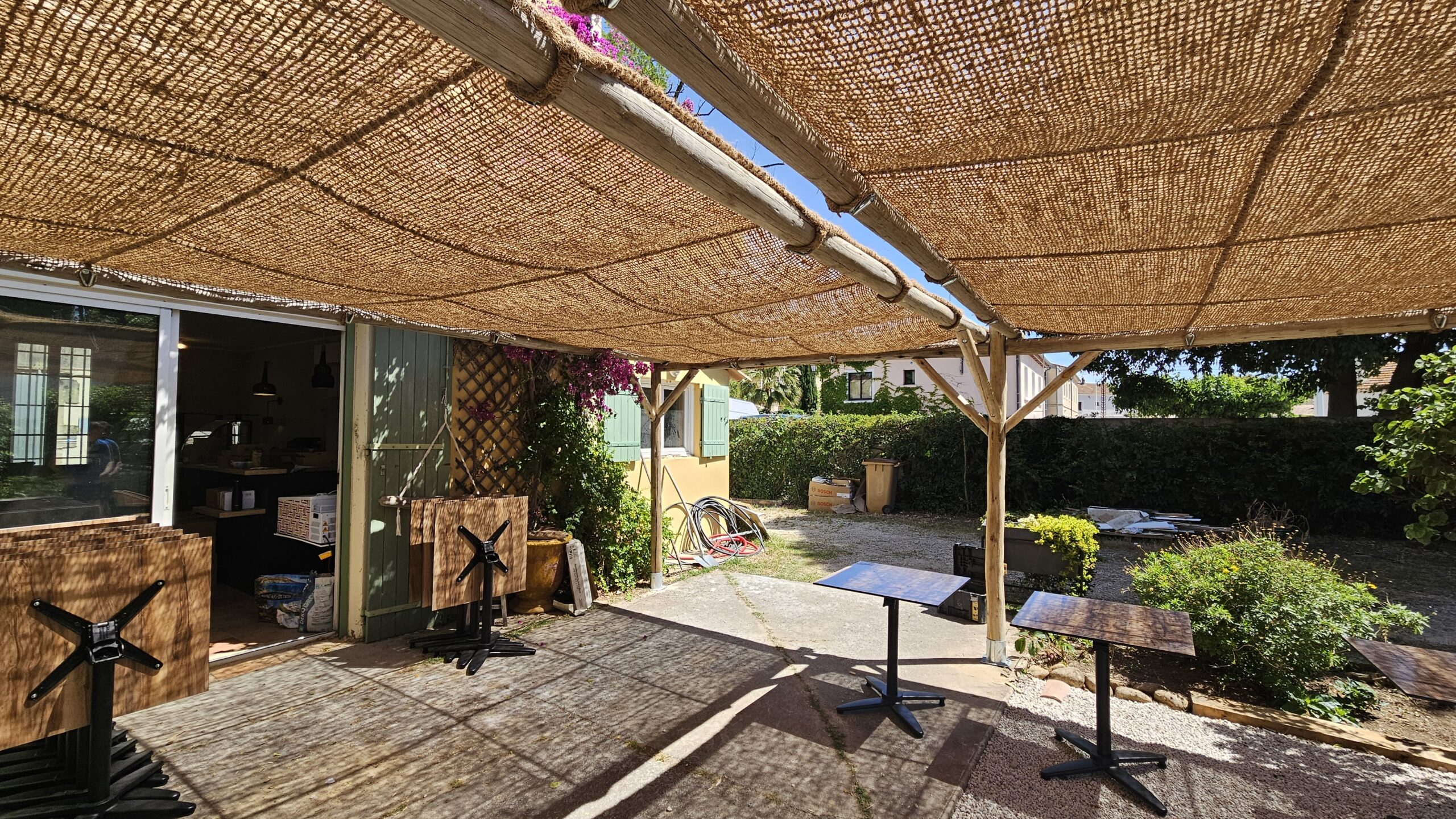 Pergola en eucalyptus avec toiture en toile coco quadrillée installée sur une terrasse professionnelle