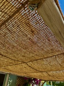 Gros plan sur une toile d’ombrage en fibre de coco tressée fixée à une poutre en bois