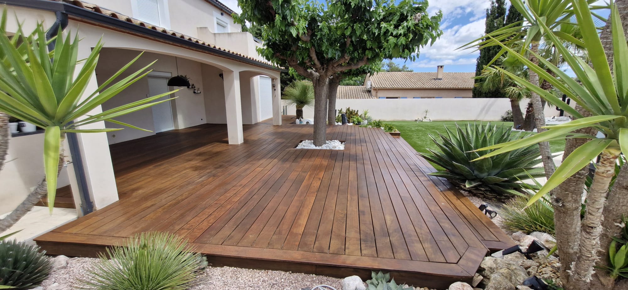 Grande terrasse en bois dans un jardin traitée avec le saturateur Protext Owatrol teinte Teck